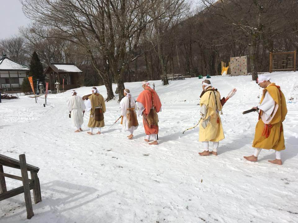 雪の中をはだしで歩く僧侶たち