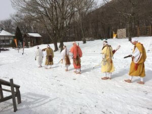 雪が積もった境内を歩く住職たち